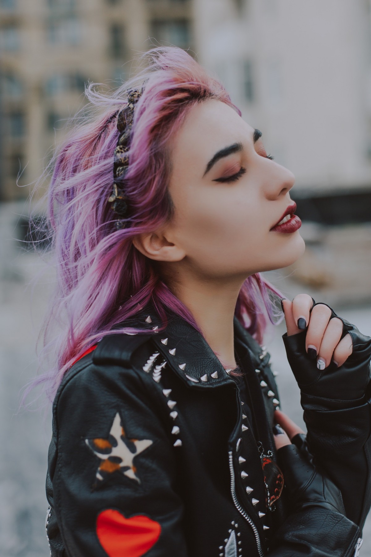 A purple haired model wears a studded black leather jacket and red lipstick for a modern twist on a punk vibe. Fashion Voyeur Blog