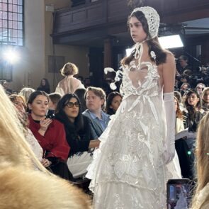An image of a model on the runway wearing a white tulle dress and bonnet from Bora Aksu's AW26 collection at London Fashion Week